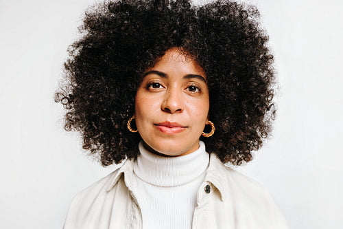 Self-confident woman with curly hair looking at the camera in a studio