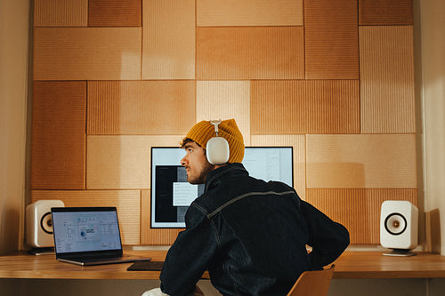 Creative man sits pensive with headphones at office desk
