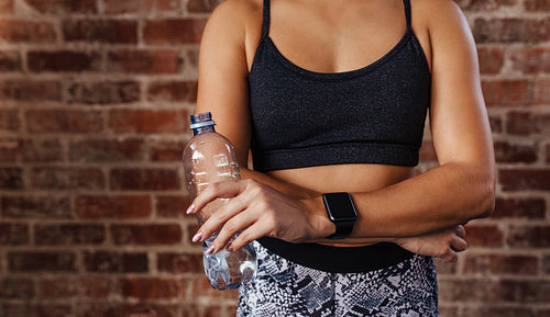 Woman in sportswear holding a water bottle.