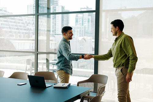 Two men shaking hands in a modern office environment