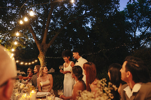 Celebration of a romantic evening wedding dinner under outdoor lights with friends