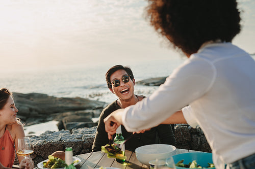 Group of friends on a vacation enjoying food and drinks at the beach