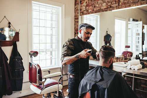 Young man getting trendy haircut at barbershop