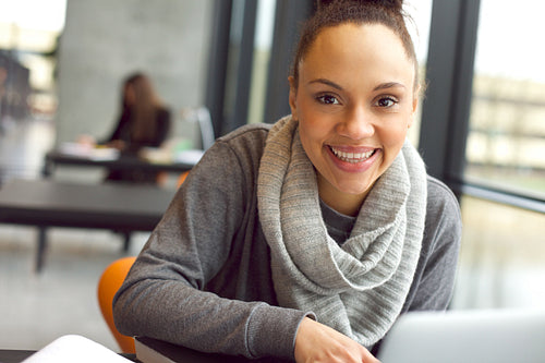 Cheerful young woman sitting in library