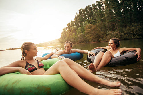 Friends floating on lake with inflatable rings