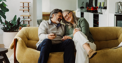 Senior man and woman hold cups and hands at home