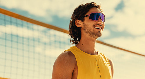 Happy male athlete playing beach volleyball in a coastal championship game