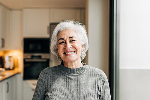 Happy senior woman smiling cheerfully at home