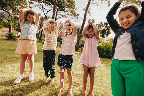 Group of excited children playing with water outdoors under the sunshine