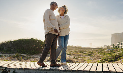 Carefree senior couple walking down a foot bridge at the beach