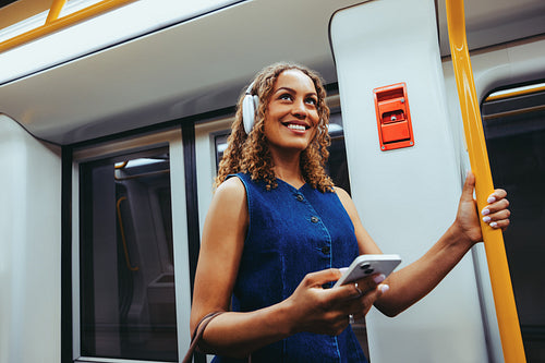 Happy woman uses smartphone on train during her commute