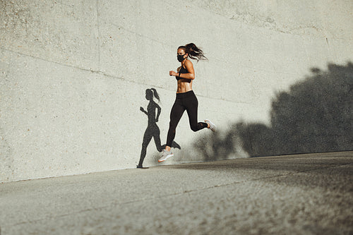 Athletic woman running wearing protective face mask