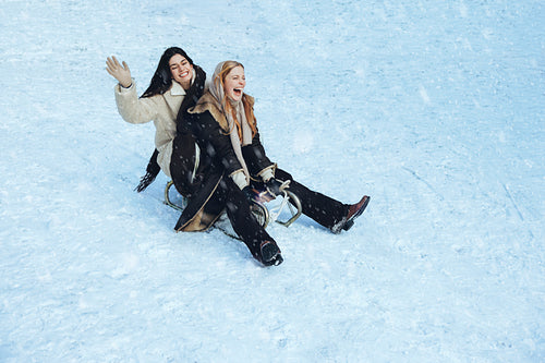 Women sledding together down a snowy hill