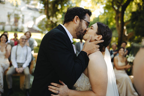 Bride and groom sharing a kiss outdoors during their wedding ceremony