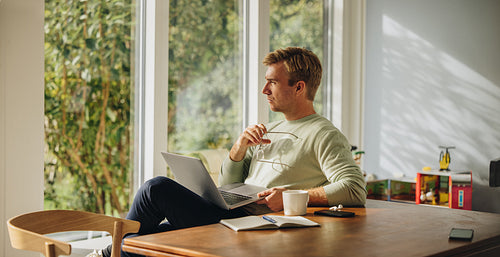 Thoughtful man with laptop at home