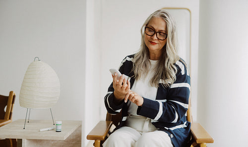 Senior woman tests glucose levels at home