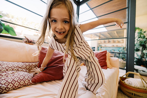 Young girl jumping on couch in bright home