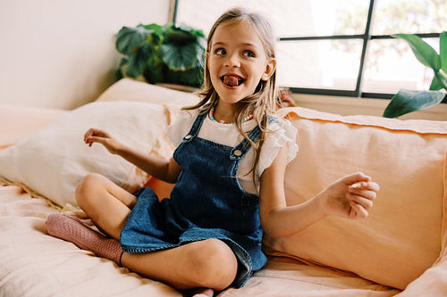 Girl plays on sofa in denim dress