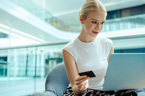 Woman enjoying online shopping at workplace using laptop
