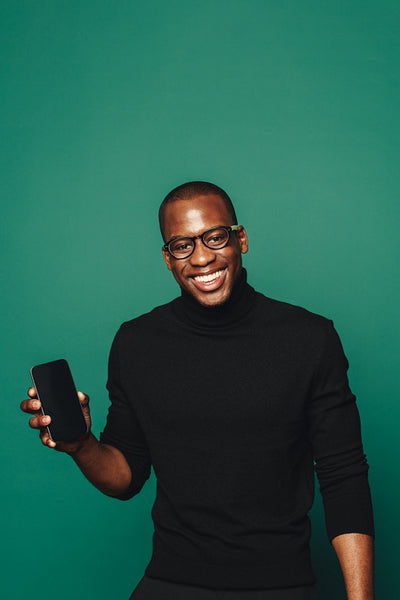 Smiling young man recommending trendy mobile app on green background