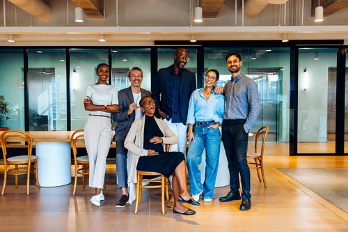 Group of professionals posing confidently in a well-lit contemporary office interior looking at the camera