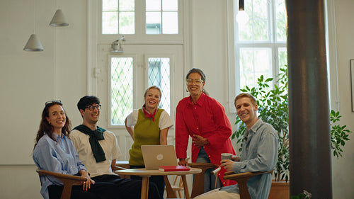 Coworkers smile together around a table in a bright startup office