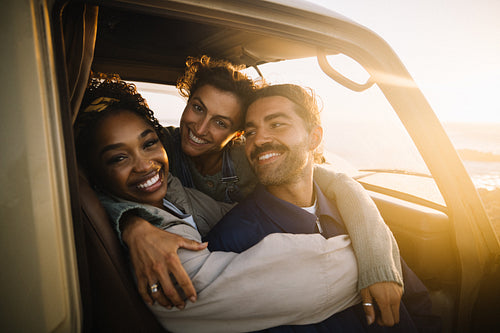 A joyful moment as friends embrace in a car at sunset