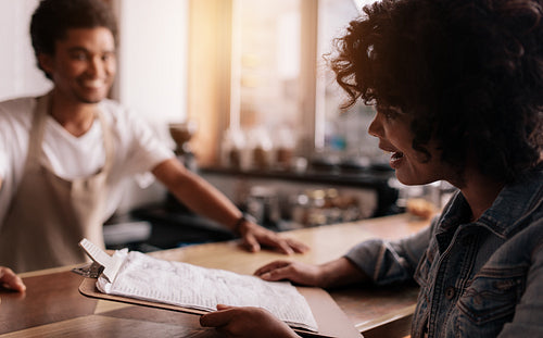 African woman giving order to barista at cafe