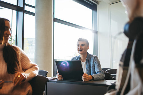 Student smiling in classroom with laptop