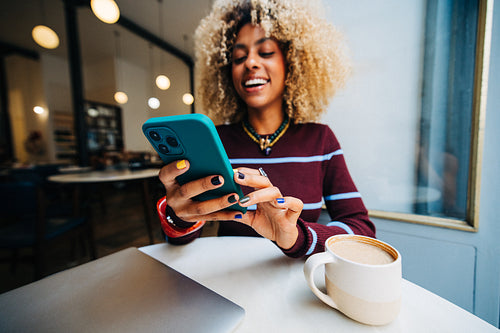 Young woman using smartphone in a cozy cafe