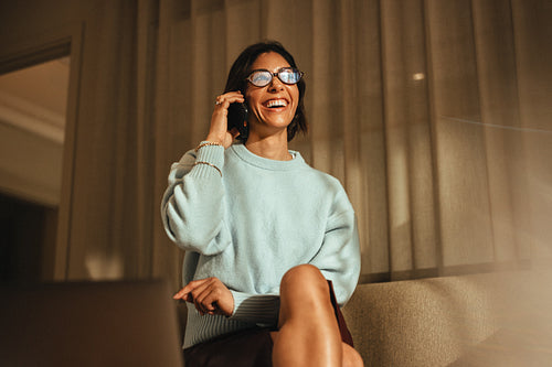 Talking business woman handles a phone conversation while sitting at home