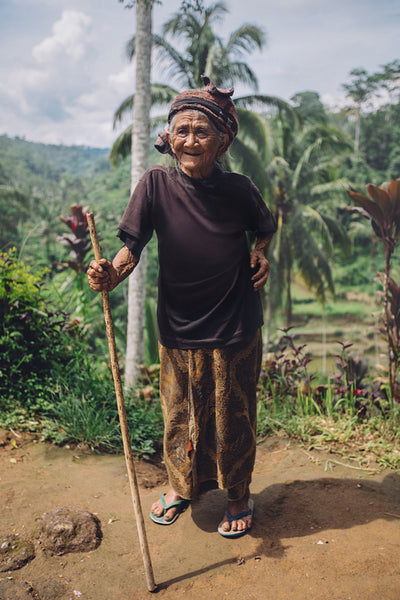 Smiling old woman standing with a stick