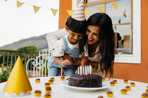 Mother and child celebrate a birthday with chocolate cake outdoors