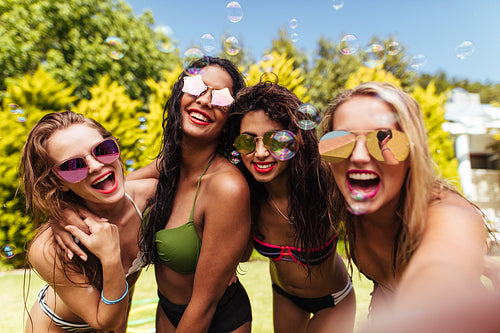 Cheerful friends taking selfie at the poolside