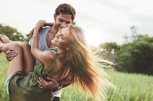 Woman being carried by her boyfriend in field