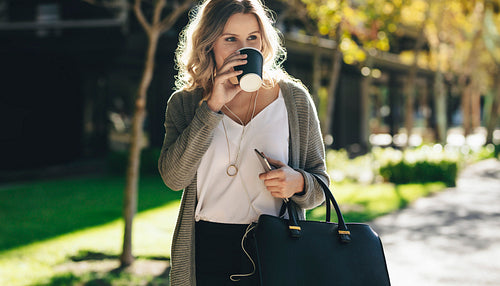 Businesswoman having coffee while commuting in the city