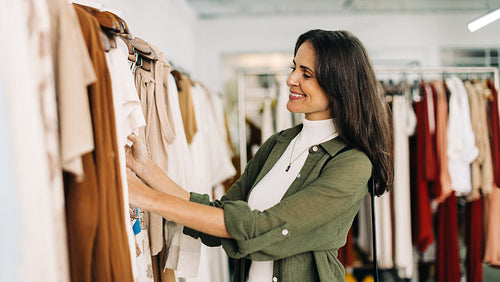 Happy female customer choosing clothing items in a fashion store