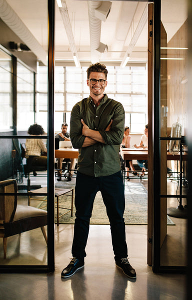 Smiling young man standing in doorway of office