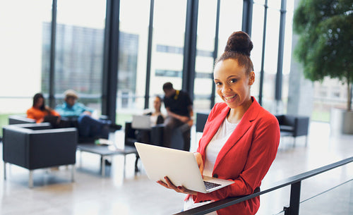 Beautiful young african woman with laptop in modern office