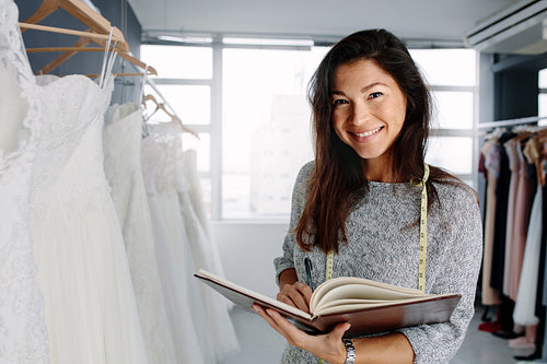 Beautiful female bridal store owner with a diary