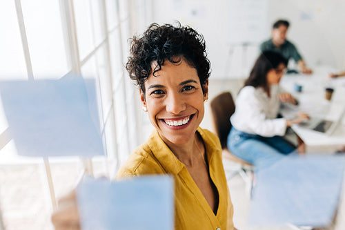 Female professional writing her ideas on sticky notes in an office