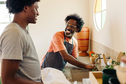 Father and son washing hands with clay filter water at the kitchen sink