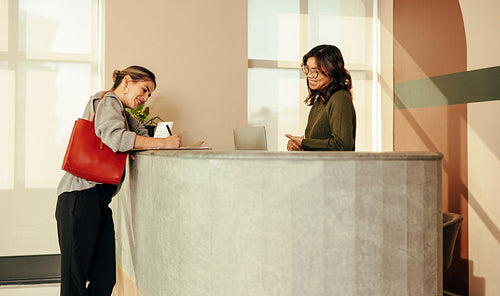 Cheerful young woman signing in to an office