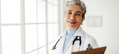 Portrait of a female doctor standing in her office and smiling at the camera