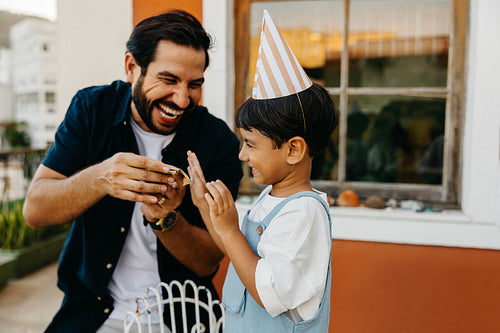 Father and son celebrating a birthday outdoors with laughter and joy