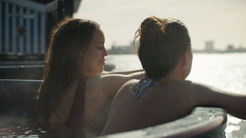 Women relaxing in outdoor hot tub at waterfront spa retreat