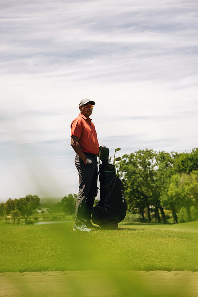 Sportsman standing with golf clubs on the course