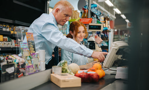 Grocery store manager training a new employee