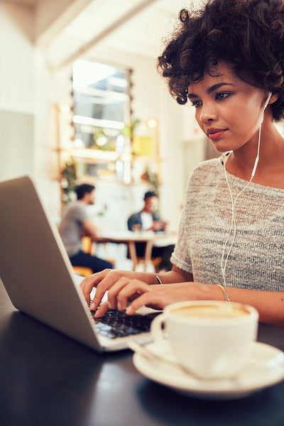 African woman at a coffee shop using laptop.