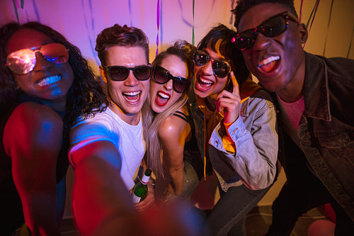 Group of friends having fun taking a selfie at a house party